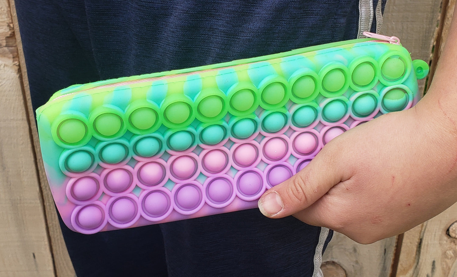 Close-up of child holding pastel pencil pouch clutched in hand.